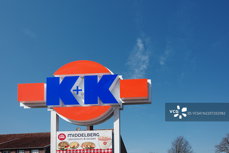 一块大胆而色彩斑斓的K + K Klaas和Kock超市招牌高高耸立在鲜艳的蓝天之下。图片素材