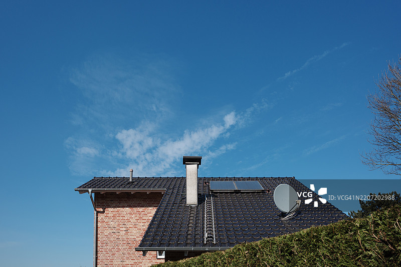 红砖外立面和深色瓦屋顶，配有银色烟囱、卫星天线和两个太阳能电池板。图片素材