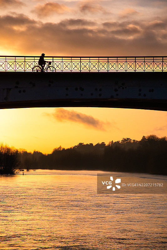 骑自行车的人穿过法国卢瓦尔河上的威尔逊桥。图片素材