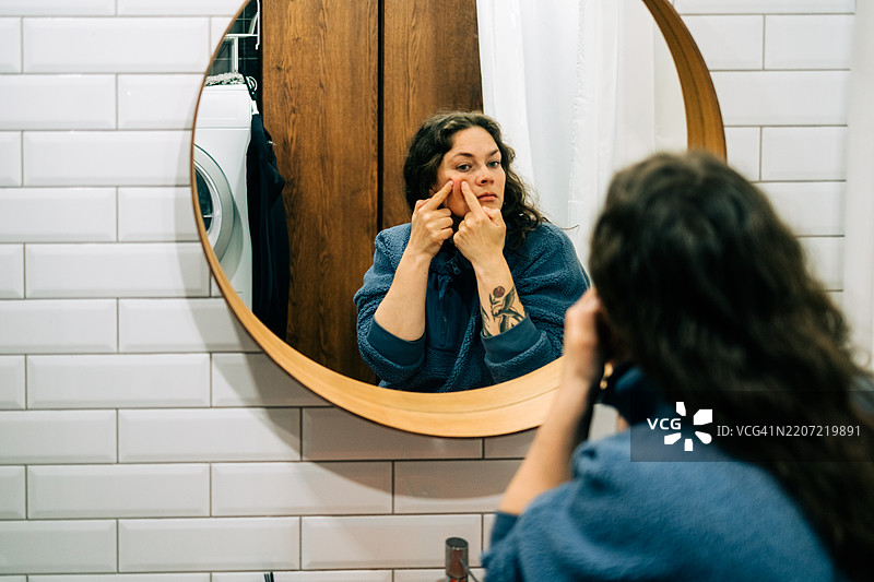 女人在浴室挤压脸上的痘痘图片素材