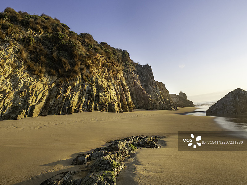 海滩上岩石和沙子上的日出光线图片素材