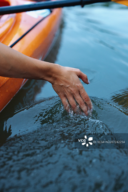 在宁静的自然河流中划皮艇时手触水面图片素材