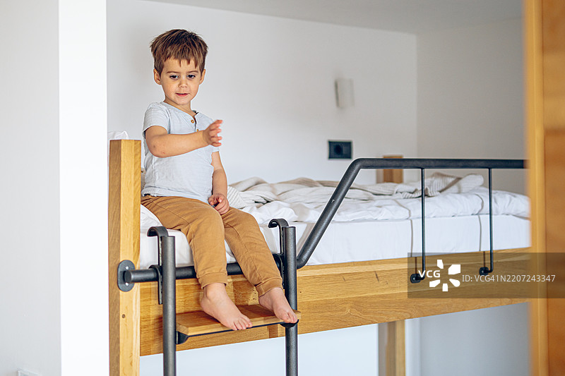 小男孩坐在双层床的顶部图片素材