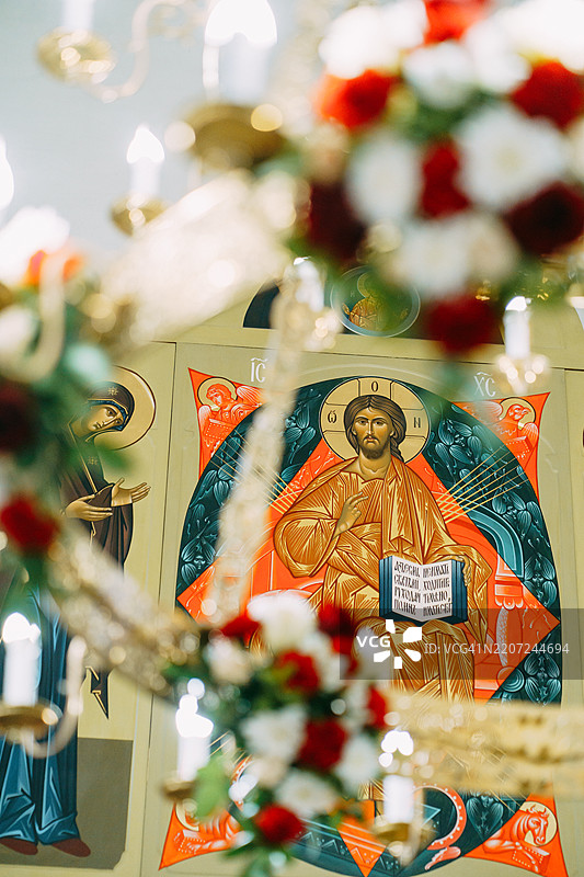东正教教堂内耶稣基督的图标，配有吊灯和鲜花图片素材