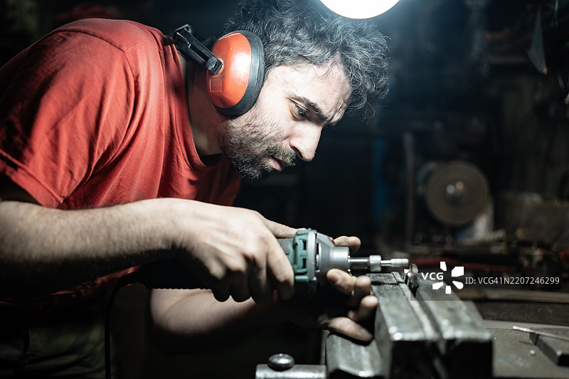 专注的工匠在工作坊环境中使用电动工具图片素材