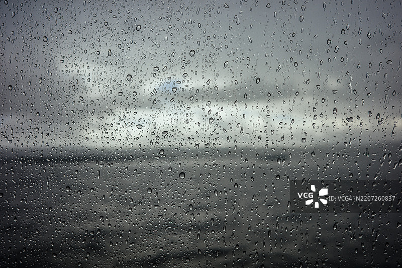 窗户上的雨滴，背景是汹涌的海浪图片素材