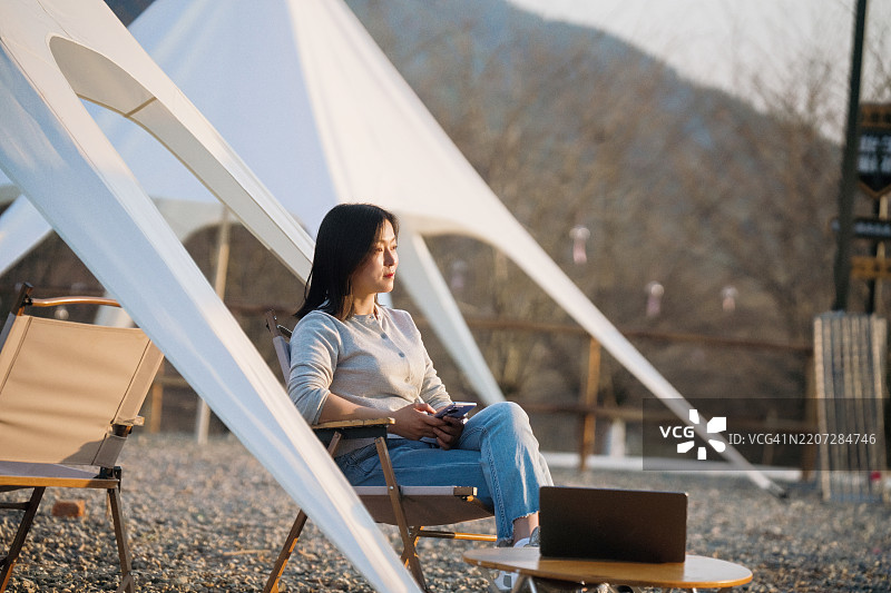 亚洲女性在露营时使用智能手机图片素材