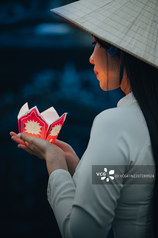 越南女孩手持花环和彩色灯笼，身穿奥黛，在越南顺化市。图片素材