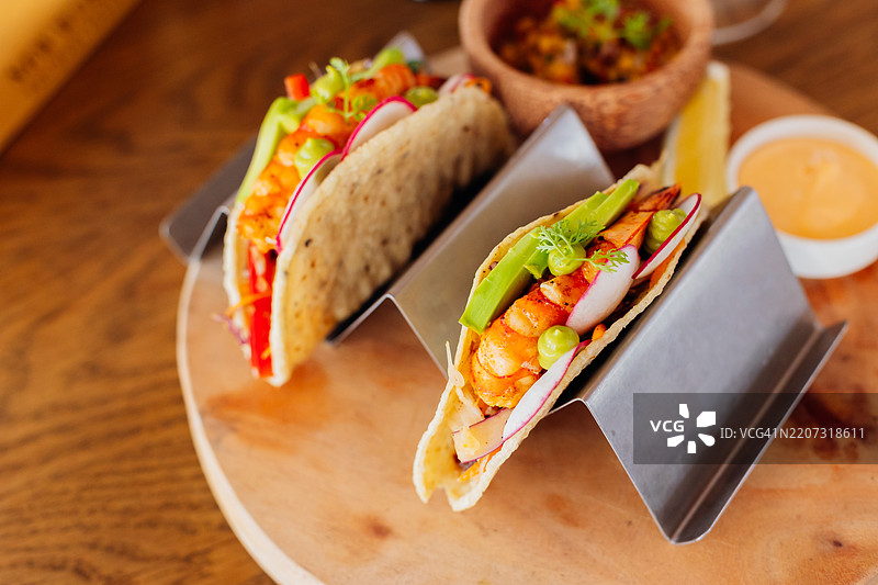 美味的虾塔可在木盘上盛放，配以新鲜的装饰图片素材