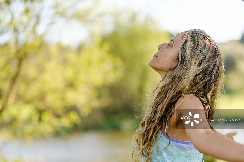 女人在大自然中呼吸新鲜空气，享受户外的宁静与安详图片素材