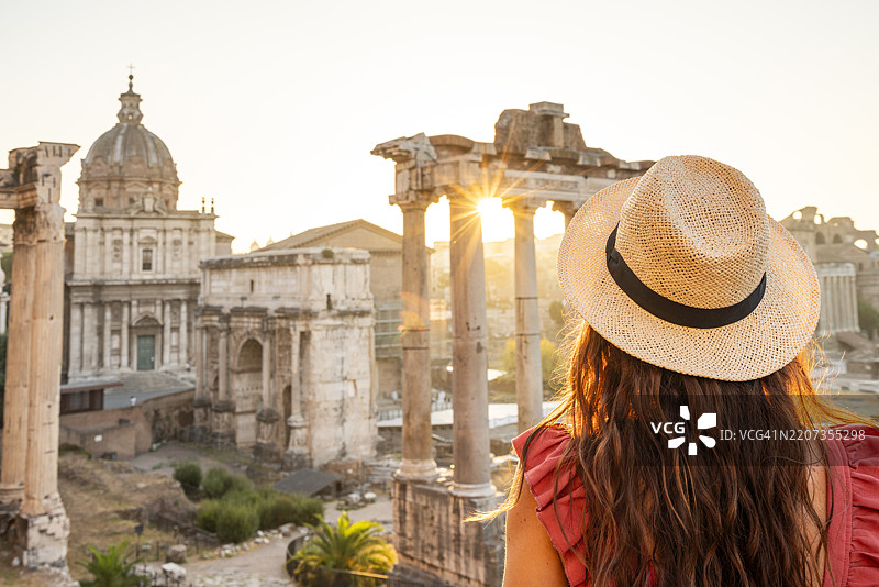 一位女性在意大利罗马的日出时分欣赏罗马广场的遗迹。图片素材