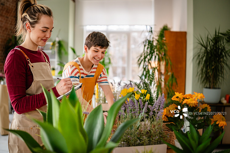 年轻女性花店老板在愉快的店铺环境中制作生动的花卉插花作品图片素材