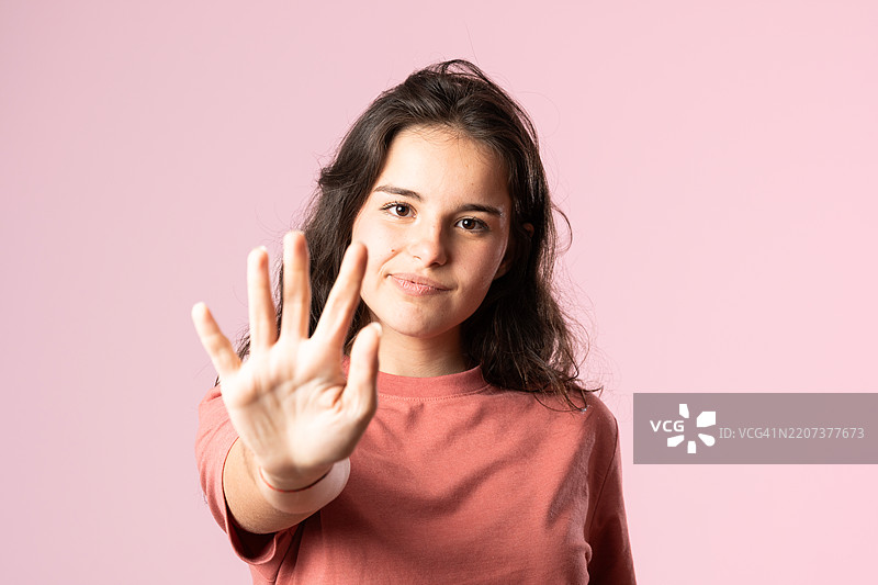 女人在粉色背景上用手做出停止的手势图片素材