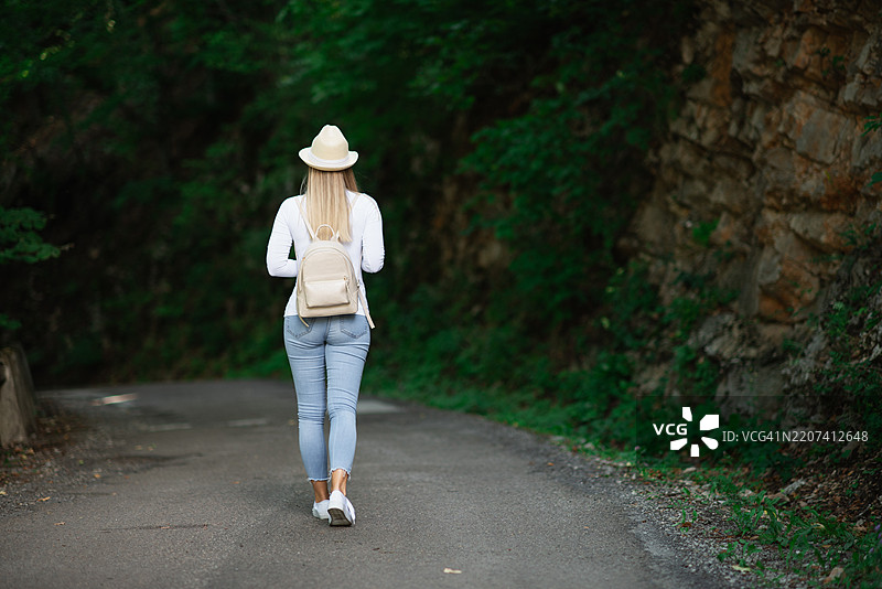 女人独自走在狭窄的森林小路上图片素材