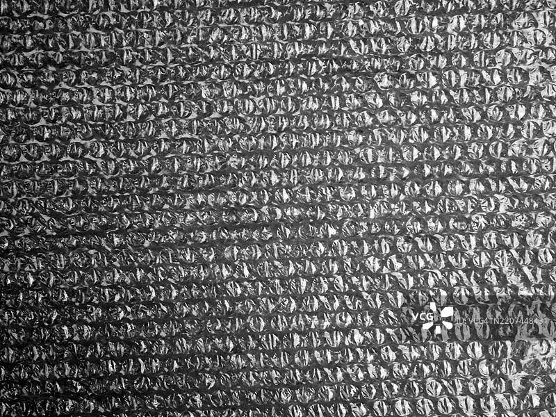 灰色气泡塑料包装，带有阴影和噪音效果。粗糙的纹理。自然光。法国巴黎。图片素材