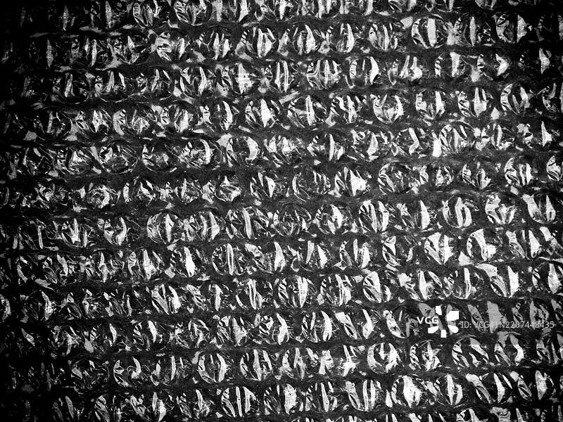 黑色气泡膜的特写。颗粒和阴影效果。粗糙的纹理。自然光。黑白色调。图片素材