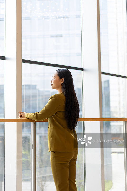 女商人在现代商务大楼的窗边站着图片素材