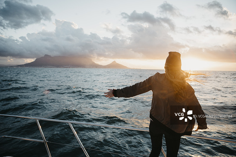 南非，年轻女性在日落时分乘船旅行，戴着毛线帽图片素材