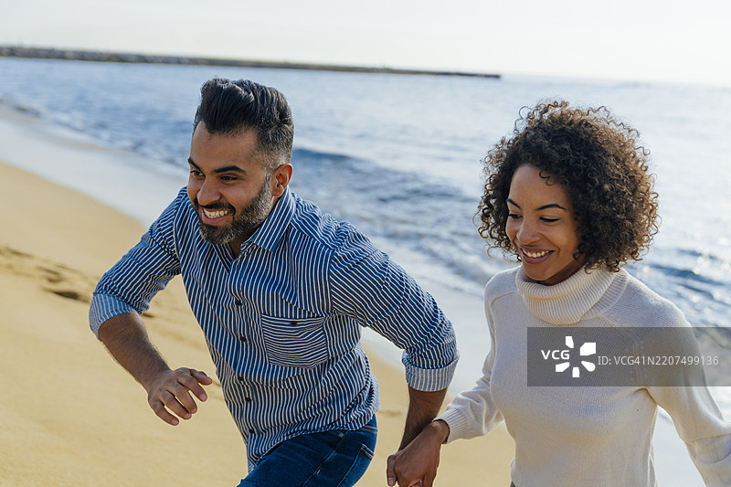 西班牙，巴塞罗那，快乐的情侣在海滩上玩耍图片素材