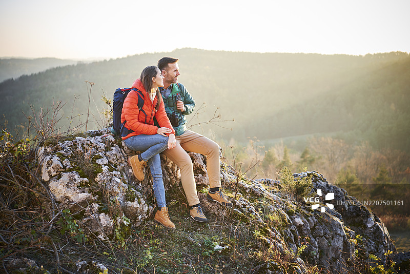 一对情侣在山中徒步旅行时坐在岩石上休息图片素材