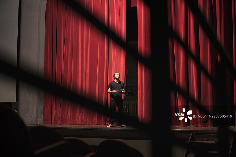 赤脚演员手持剧本站在剧院舞台上图片素材