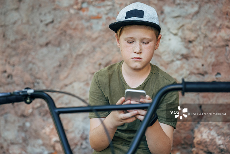 骑着BMX自行车的男孩在使用手机图片素材