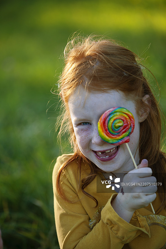 快乐的女孩用棒棒糖遮住眼睛图片素材