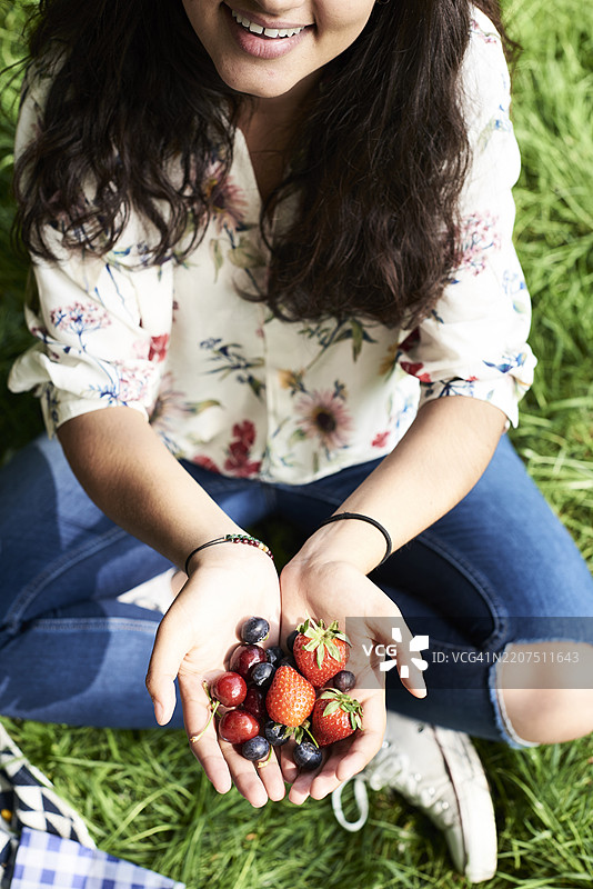 从上方俯视在公园野餐的女人展示浆果图片素材