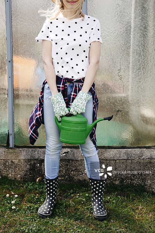 年轻女性手持绿色浇水壶图片素材