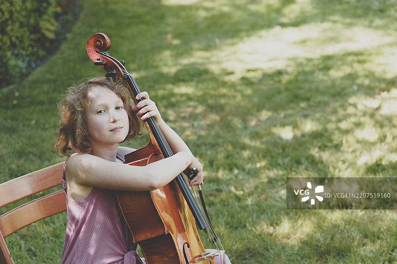 花园里拿着大提琴的女孩图片素材