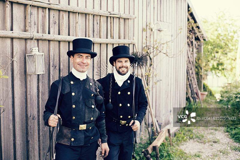 两个微笑的烟囱清扫工站在木墙前图片素材