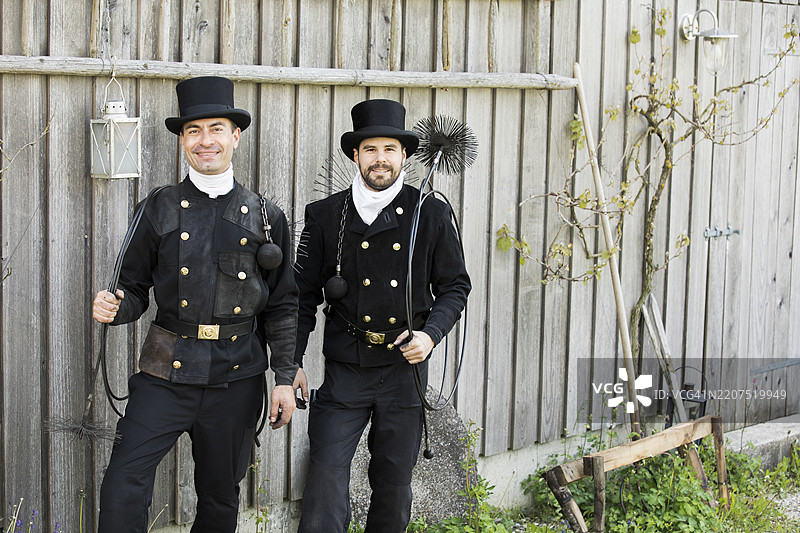 两个微笑的烟囱清扫工站在木墙前图片素材