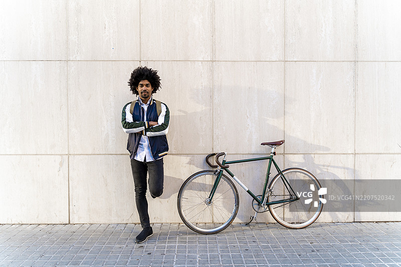 休闲商务人士骑自行车站在墙边的肖像图片素材