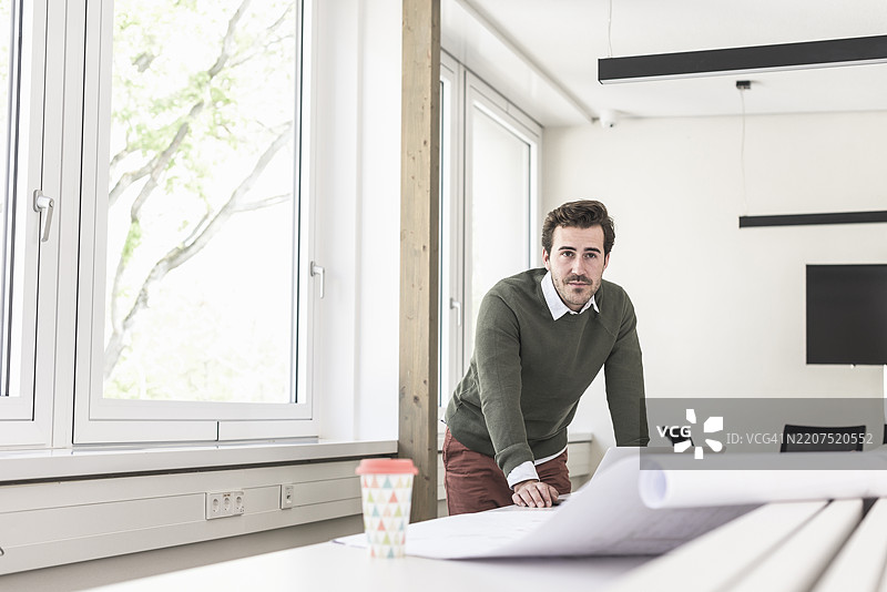 年轻建筑师在明亮的办公室中绘制蓝图图片素材