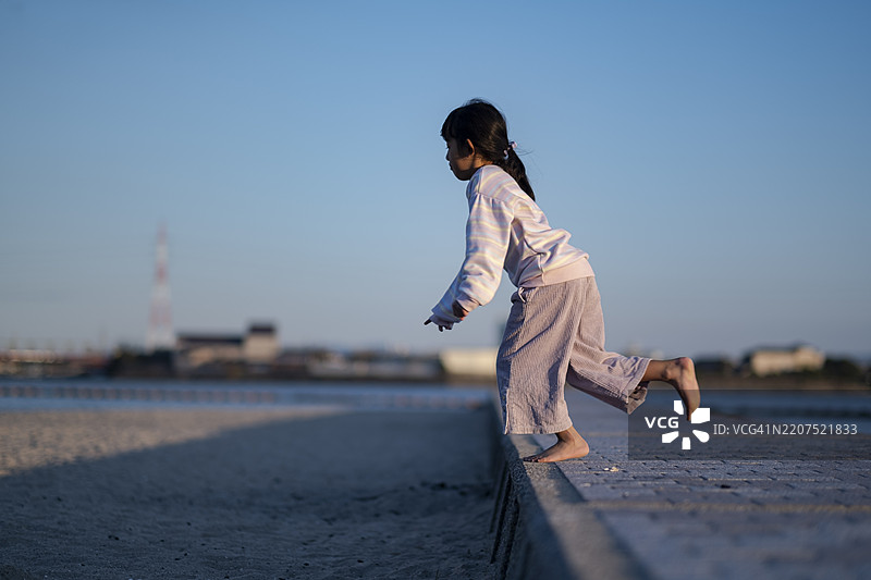 女孩赤脚在沙滩上跳跃图片素材