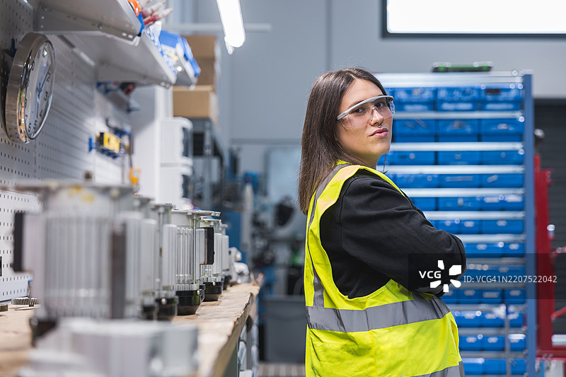 年轻女性在工厂里佩戴安全眼镜的肖像。图片素材