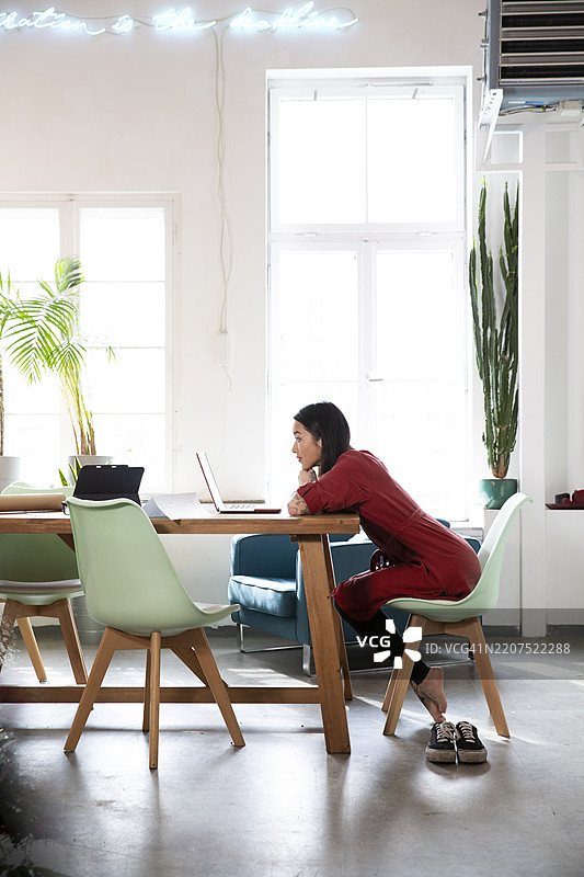 女性在现代办公室的桌子上使用笔记本电脑图片素材