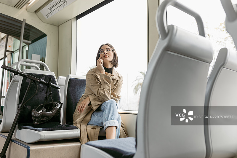 女人坐在电动滑板车上，目光投向一旁。图片素材