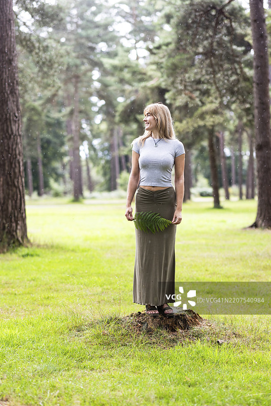 女人站在森林中树木旁的岩石上图片素材