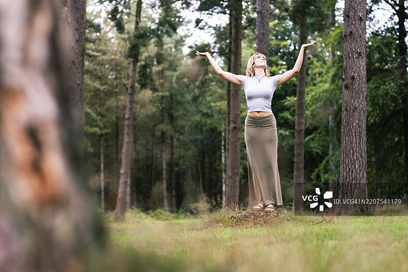 女人在树前双臂高举站立图片素材