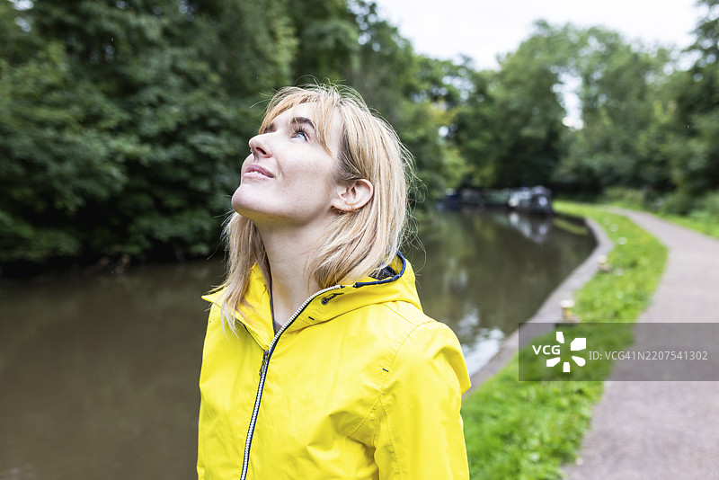微笑的女性穿着黄色雨衣，站在树旁图片素材