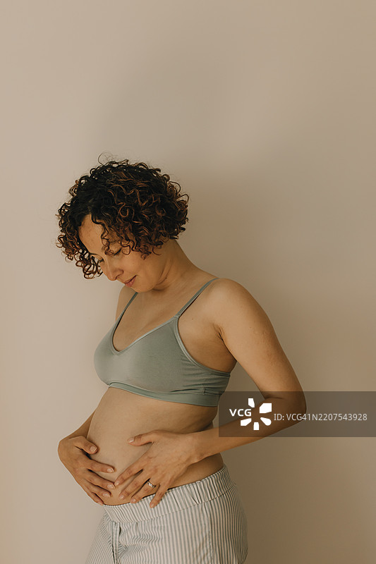 孕妇在家靠墙触摸肚子图片素材