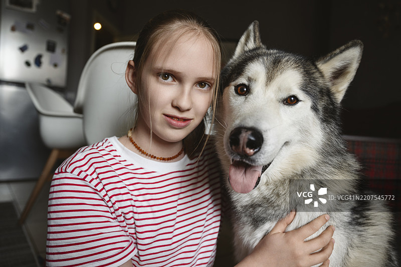 年轻女孩与哈士奇犬在家中图片素材