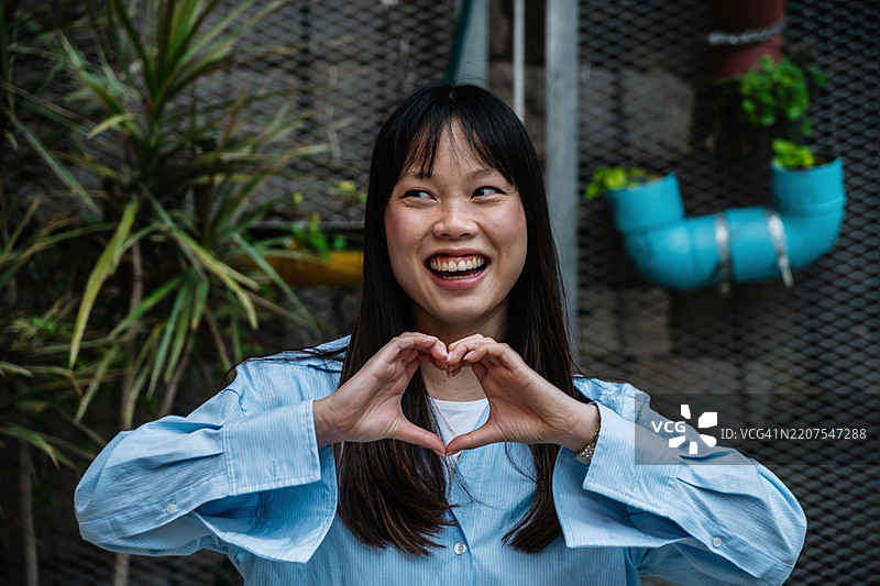 在巴塞罗那户外微笑的女性用双手做出心形。图片素材