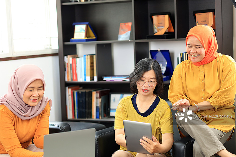 三位印尼朋友共享使用笔记本电脑的时刻图片素材