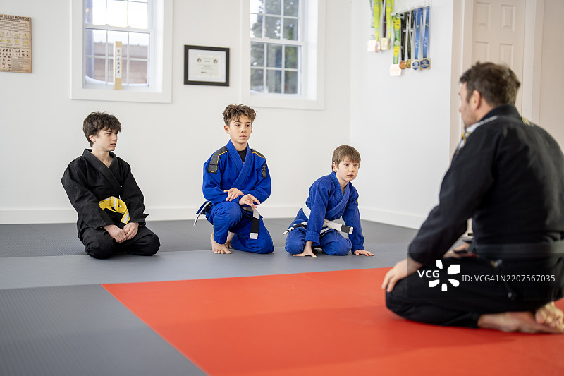 年轻男孩在教练指导下在健身垫上练习武术图片素材