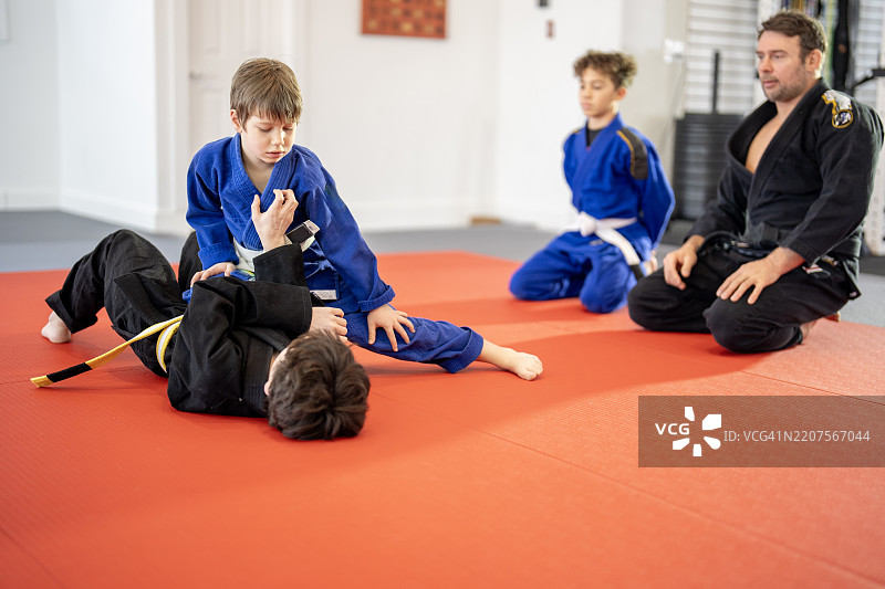 男孩们在教练的指导下学习巴西柔术技巧的训练课图片素材