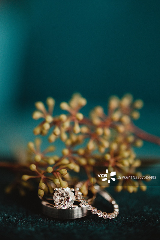 青色天鹅绒背景上的钻石婚戒，留有空白空间图片素材