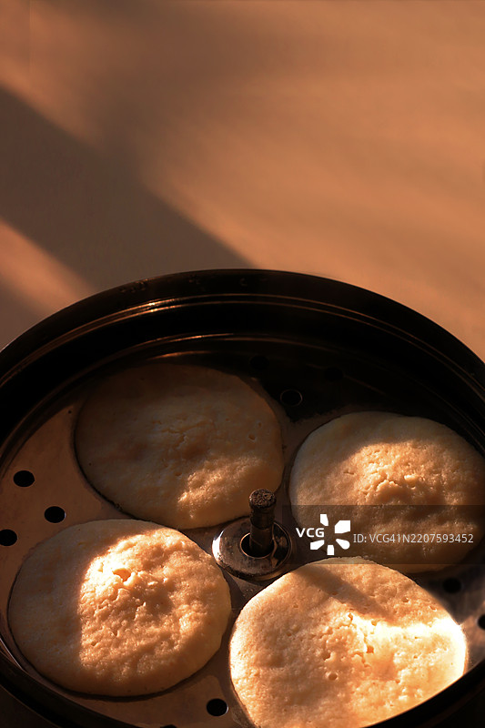 蒸汽腾腾的热米糕在米糕蒸锅中，晨光照耀下的印度早餐图片素材