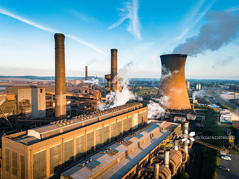 日落时分，钢铁厂冒出烟雾和蒸汽，航拍视角图片素材